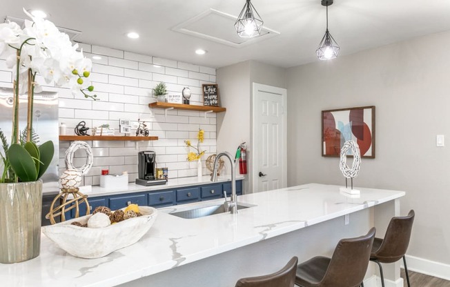 a kitchen with white countertops and a large white island with a sink and three chairs