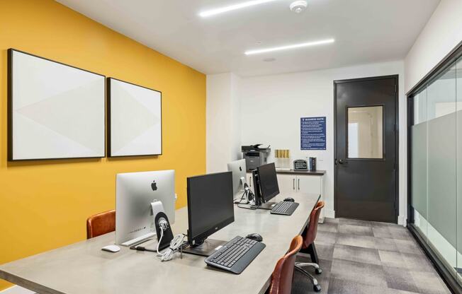 our office is equipped with a large desk with computers and a yellow wall