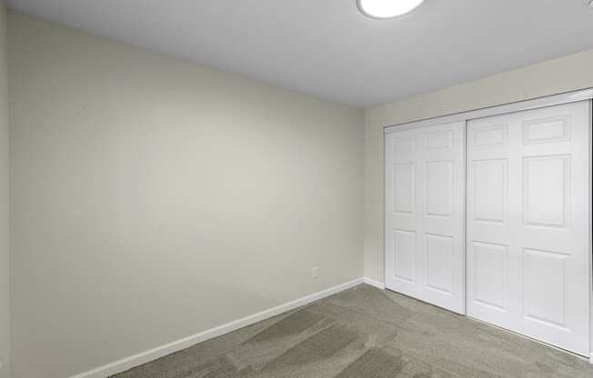 a bedroom with two closet doors and a carpeted floor at Swiss Gables Apartment Homes, Kent, WA