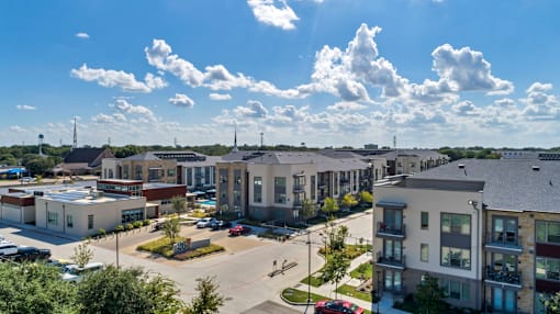 A sunny day at a residential complex with multiple buildings and cars parked.