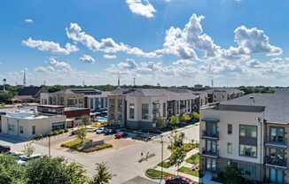 A sunny day at a residential complex with multiple buildings and cars parked.