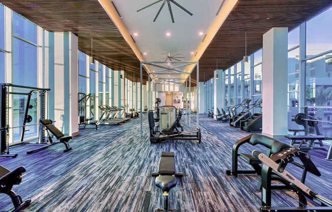 A gym with a variety of equipment including treadmills, weights, and exercise machines.