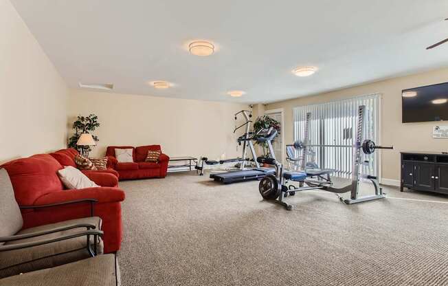 A living room with a red couch, a blue exercise bike, and a TV.