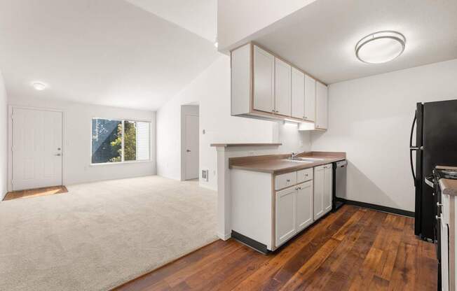 A kitchen with white cabinets and a black fridge at Clackamas Trails Apartments, Oregon, 97222