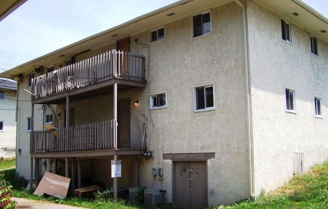 an apartment building with two balconies and a sidewalk