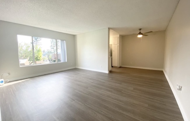 an empty living room with wood floors and a large window