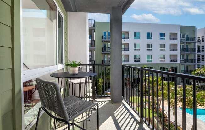 A balcony with a table and chairs overlooking a pool.