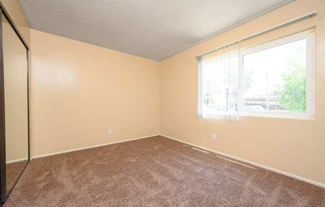 a bedroom with a large window and a carpeted floor at Oak Terrace Senior Apts, California