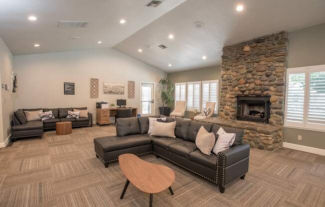 A clubhouse lounge with a stone fireplace and grey couches at Zinfandel Village Apartments, California, 95670