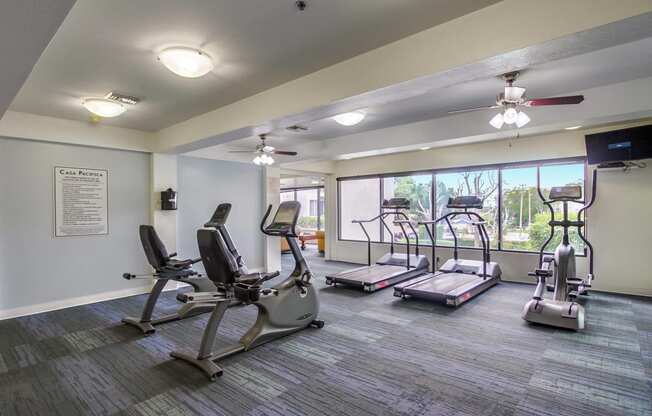 a gym with exercise machines and a window
