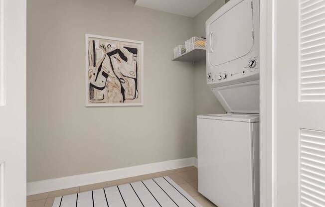 A white fridge in a room with a framed picture on the wall.