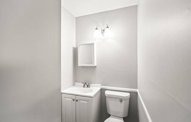 A white bathroom with a toilet, sink, and medicine cabinet.