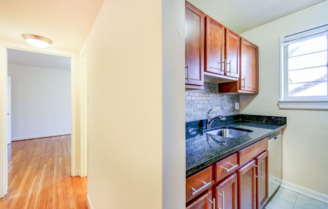 kitchen with wood cabinetry, tile backsplash, and window at cambridge square apartments in bethesda md