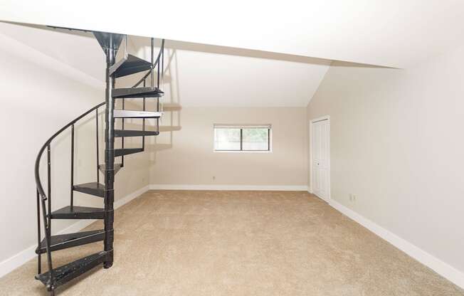 a small attic room with a spiral staircase and a window