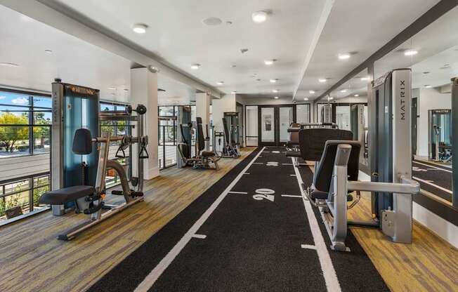 A gym with a variety of equipment including treadmills, weights, and exercise machines.