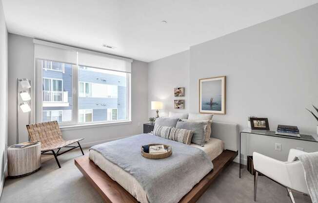 A bedroom with a large bed, a chair, and a desk.