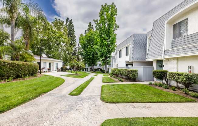 a street view of a white apartment with a gray roof and manicured lawns