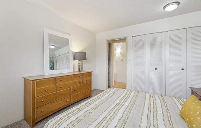 A bedroom with a wooden dresser and a striped bedspread.