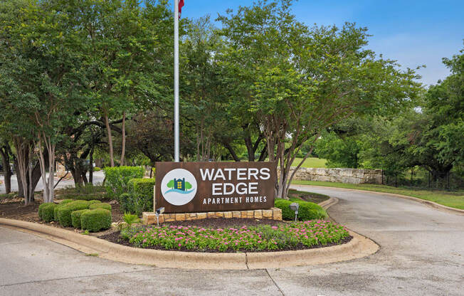 a sign that says waters edge apartments with trees in the background