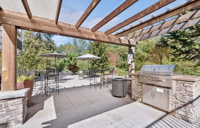 a patio with a grill and tables with umbrellas