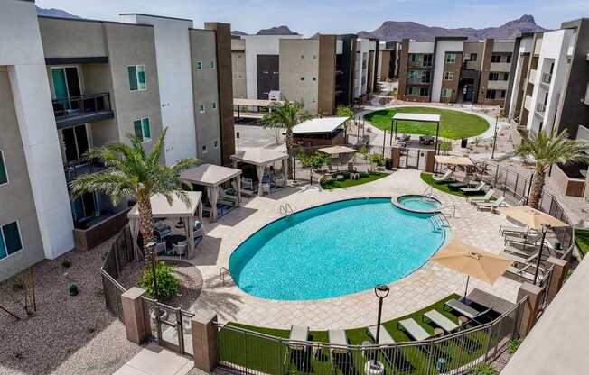 A pool surrounded by a fence and chairs in a courtyard.