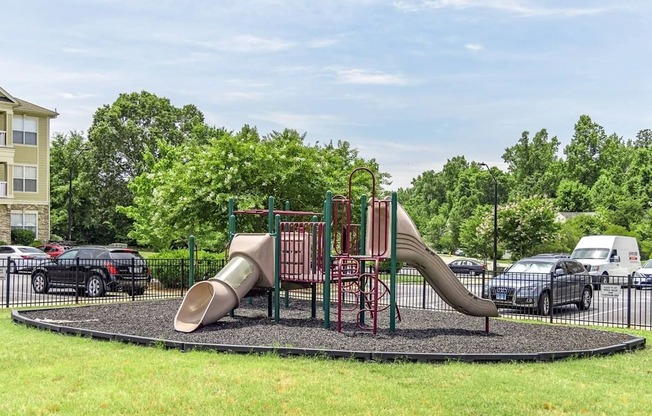 A playground with a slide and a green lawn.