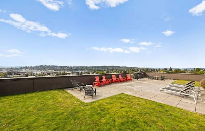 A patio with red chairs and a table is set up on a grassy area.