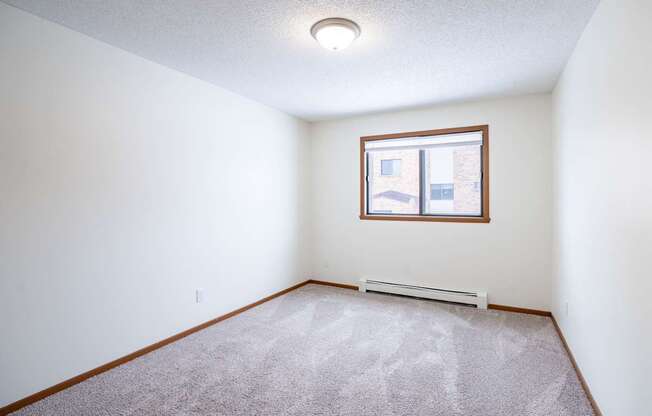 A room with a carpeted floor and a window. Fargo, ND Westwood Estates