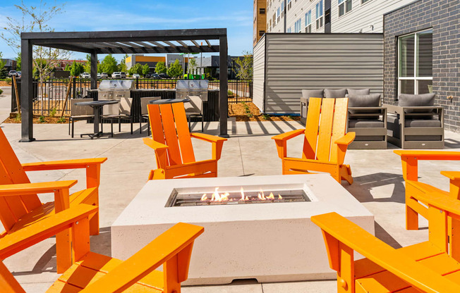 A patio with orange chairs and a fire pit.