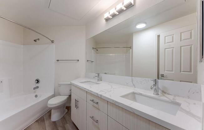 A white bathroom with a toilet, sink, and bathtub.