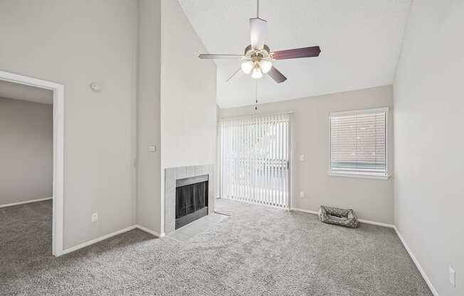 A spacious living room with a fireplace and a ceiling fan.
