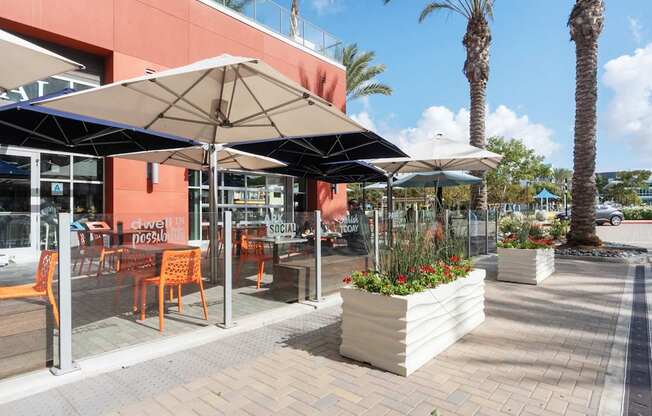 A sunny day at a cafe with orange chairs and umbrellas.