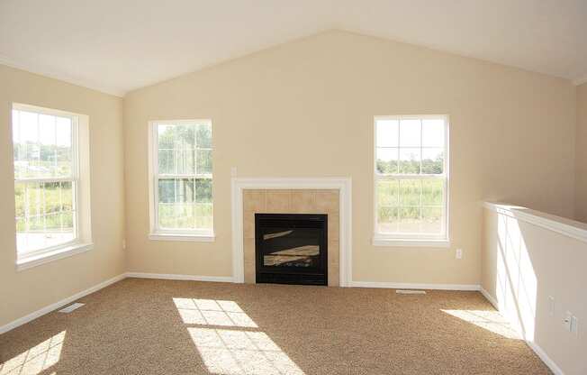 A living room with a fireplace and windows at Lynbrook Apartment Homes and Townhomes, Elkhorn