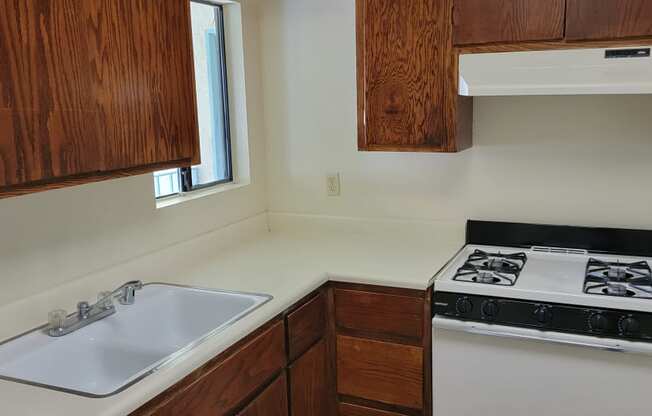 Kitchen with gas stove and spacious wood stained cabinets at Magnolia Apartments in Riverside, California.