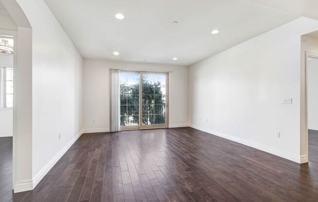 an empty living room with white walls and a sliding glass door