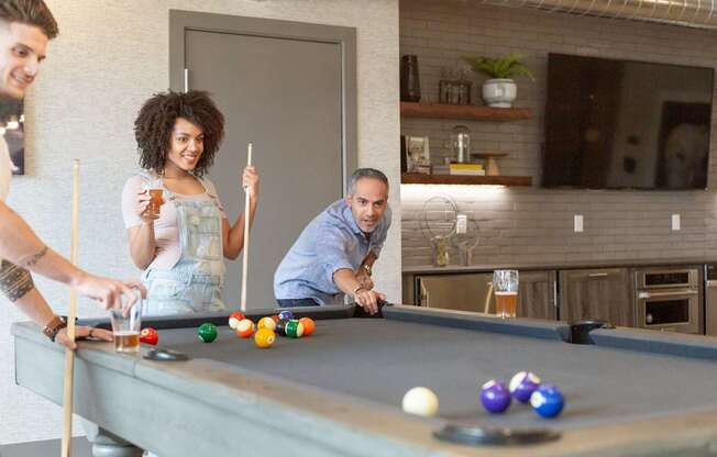 Three people playing pool in a room.