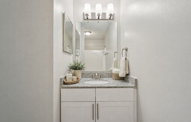 A bathroom with a sink, mirror, and cabinet.