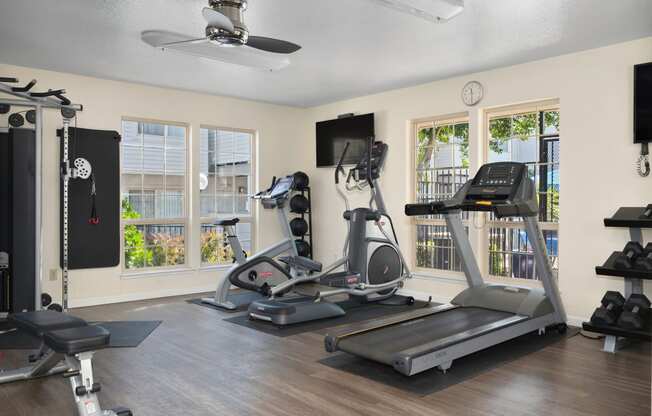 two treadmills and other exercise equipment in a gym with windows