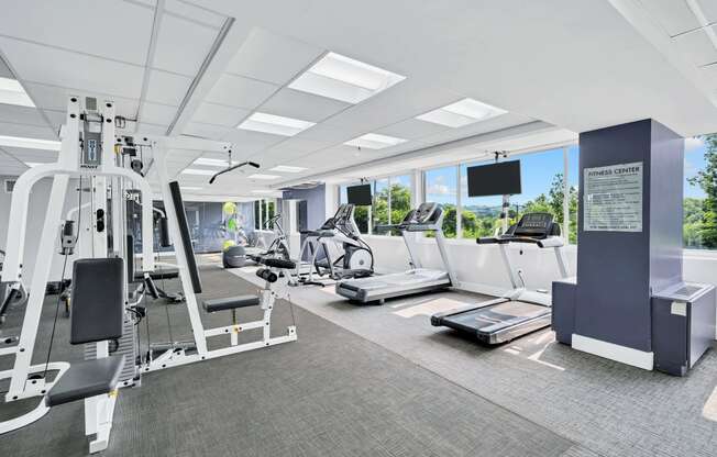 a gym with treadmills and other exercise equipment in a room with windows