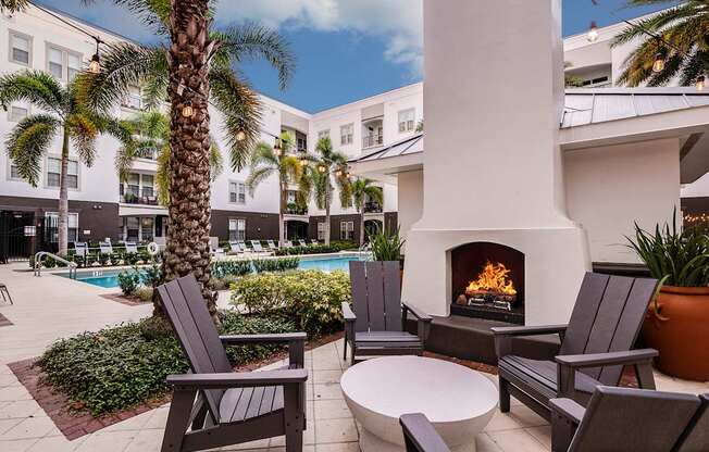 A patio with a fireplace, chairs, and a table.