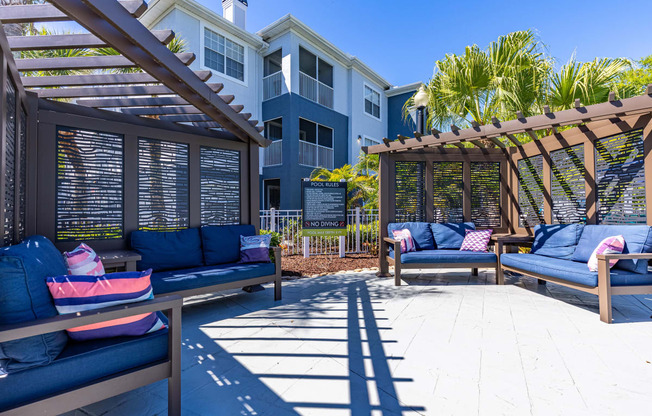 a patio with blue couches and a wooden pergola