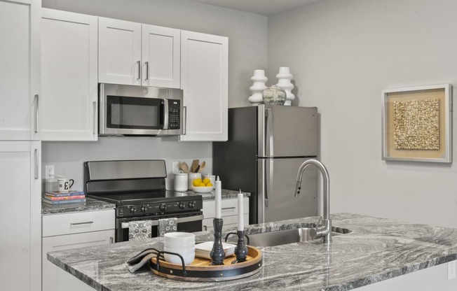 a kitchen with a marble counter top and a stainless steel refrigerator at The Edison at Chapel Hills, Colorado Springs, 80920