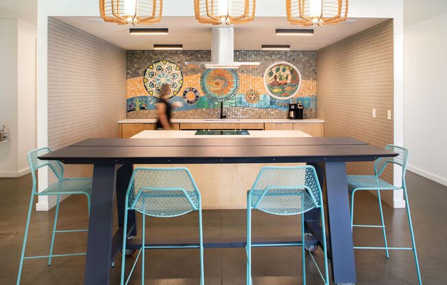 a large table with blue chairs in front of a mosaic wall