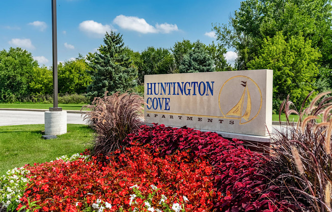 A sign for Huntington Cove Apartments is surrounded by flowers