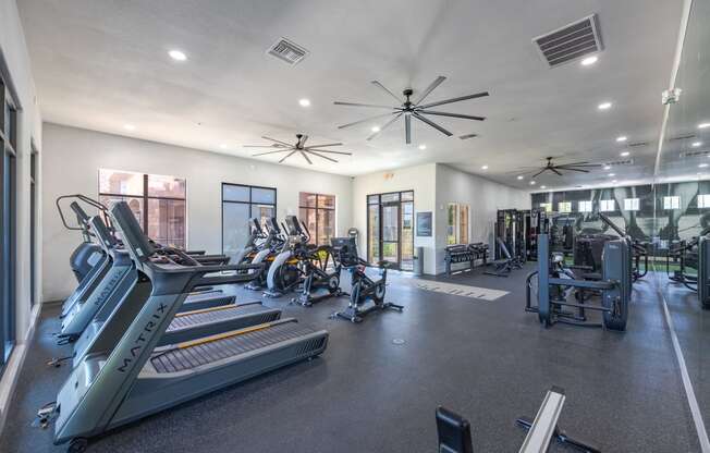 a spacious fitness center with cardio equipment and windows