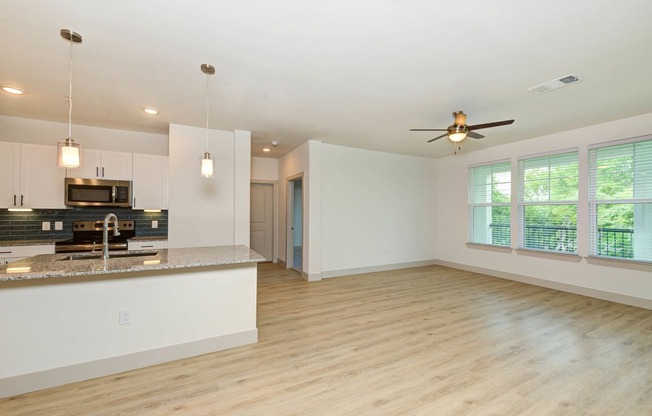 an empty living room with a kitchen and a ceiling fan at Legacy at Cibolo, Boerne