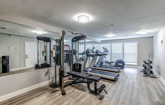 a gym with treadmills and other exercise equipment in a room with a mirror