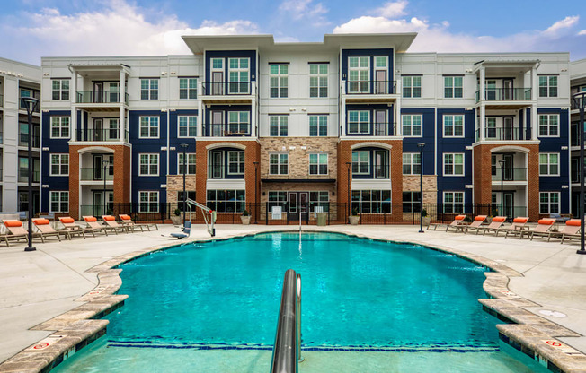 a swimming pool in front of an apartment building at The Bella at Westchester, Midlothian, VA