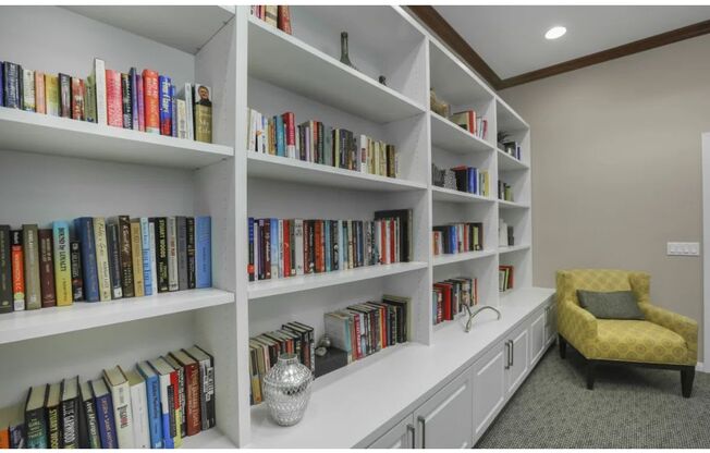 a large book shelf with many books and a yellow chair at Tesoro Senior Apartments, Porter Ranch, CA, 91326