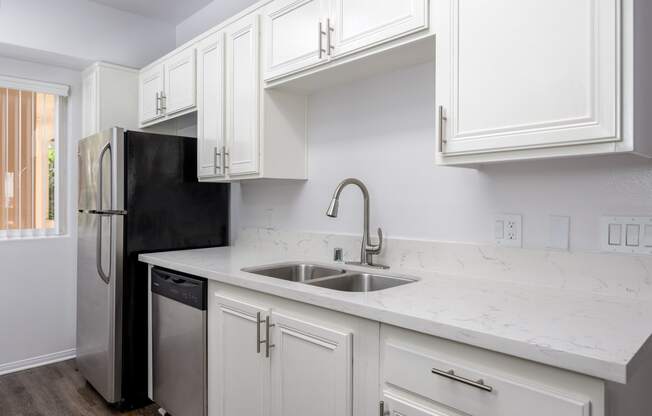 a kitchen with white cabinets and a sink and a refrigerator